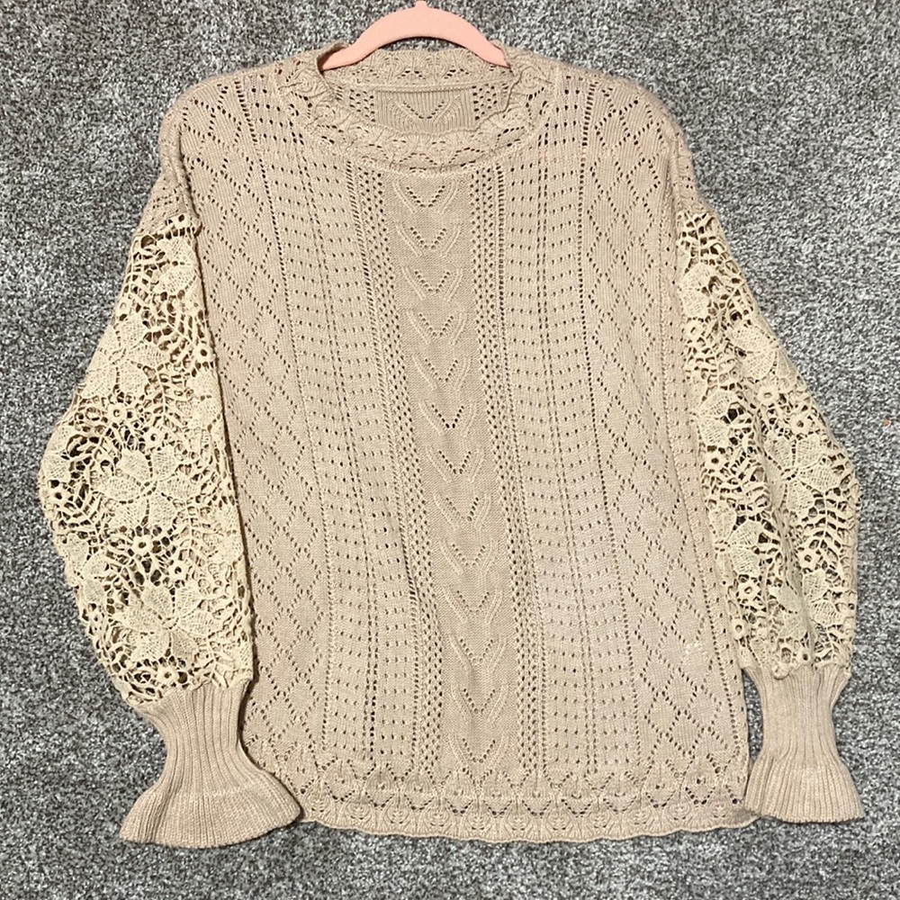 Cream sweater with knitted detailing.